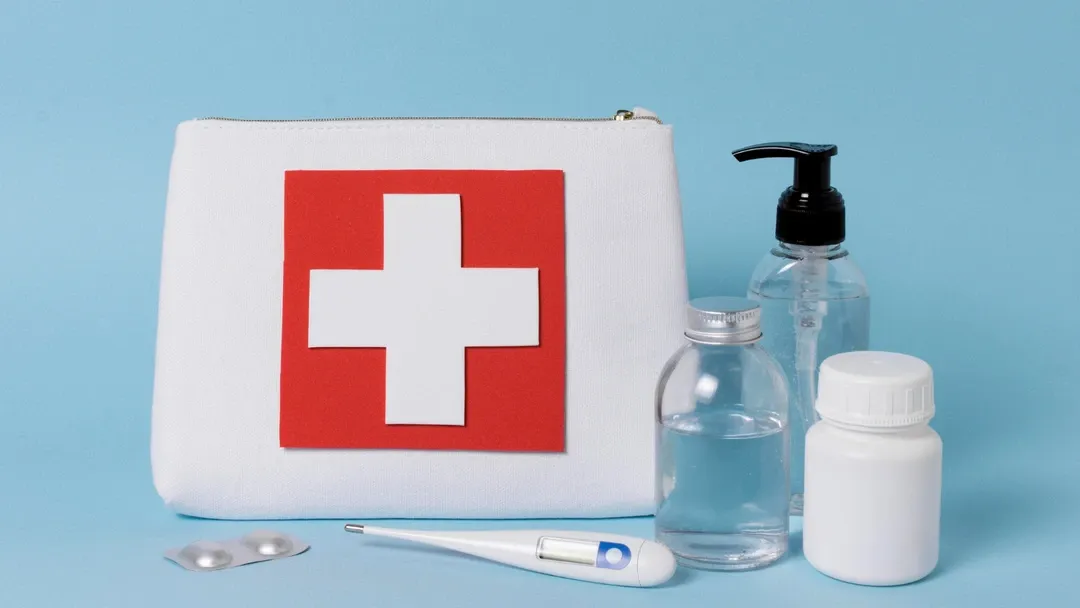 First aid kit with medical supplies, including bottles, pills, and a thermometer, for emergencies