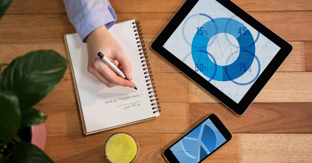Workspace featuring a notebook, tablet, and phone for strategic business planning
