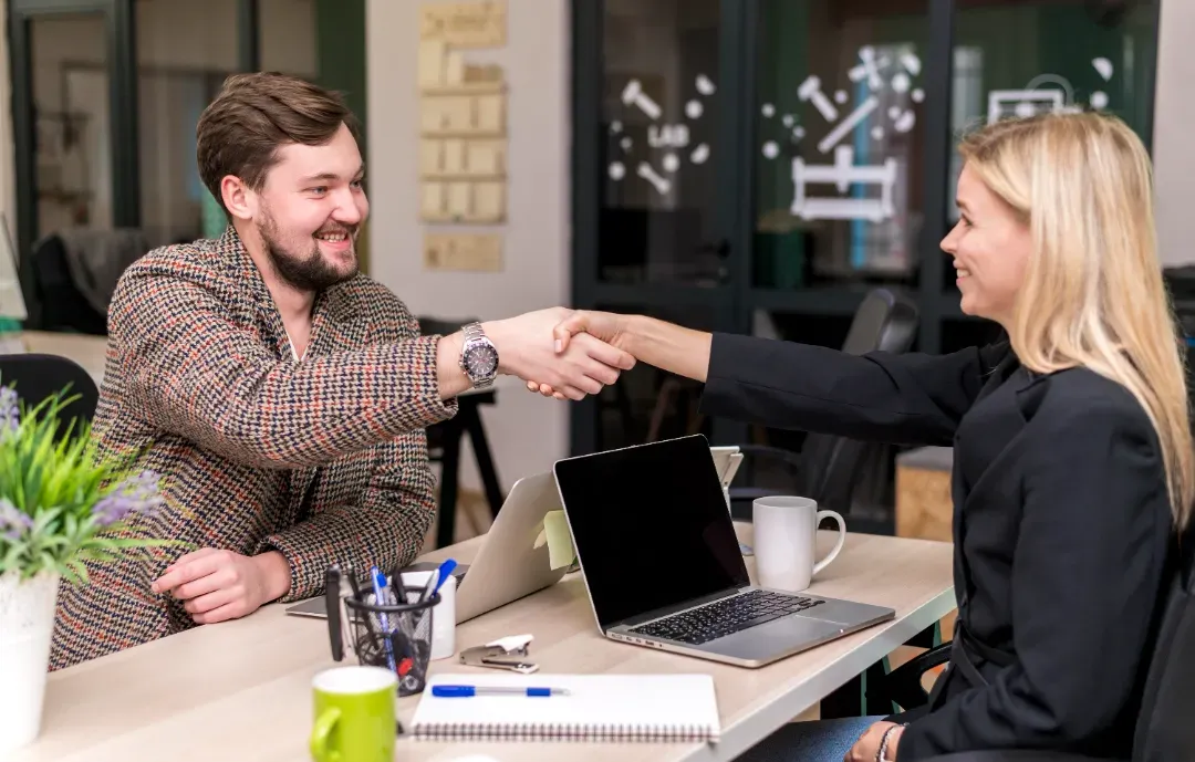 Happy client shaking hands with service provider in a modern workspace