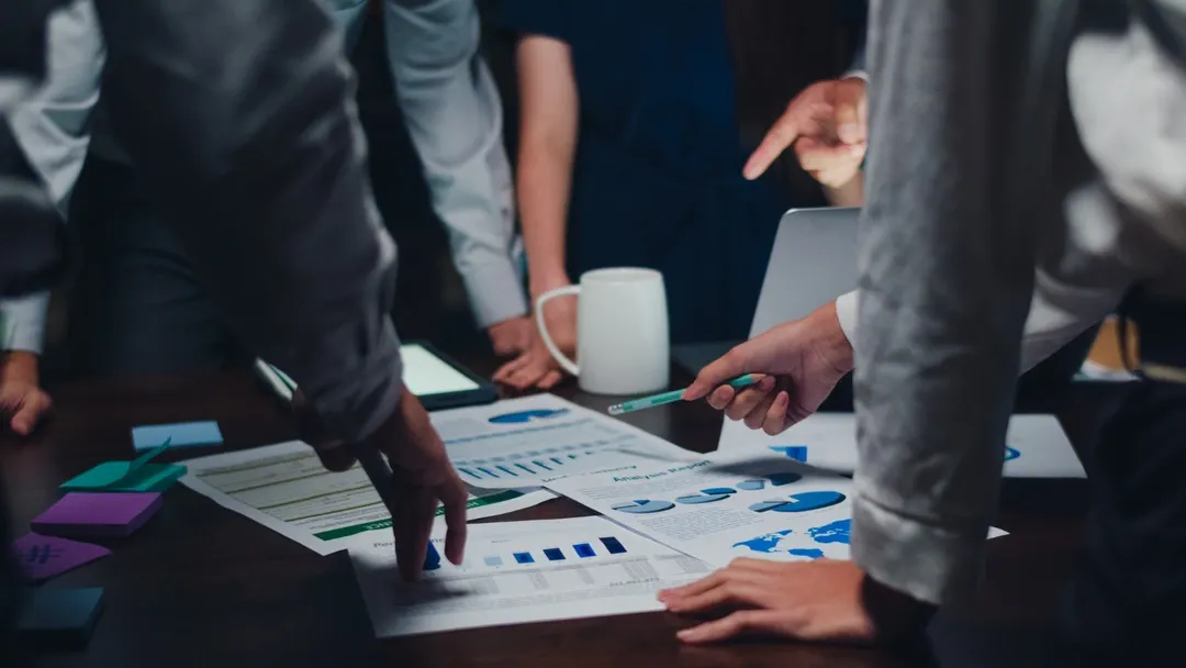 People collaborating over a table with charts, representing car rental business planning